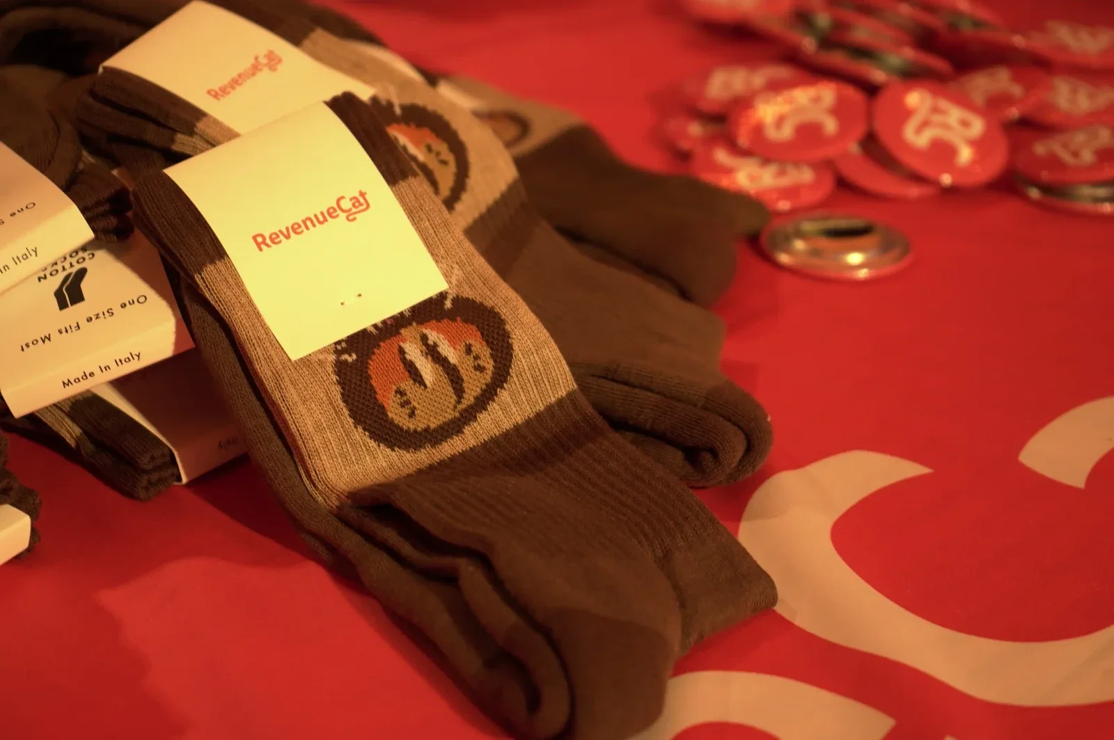 RevenueCat branded socks and badges laid out on a red table
