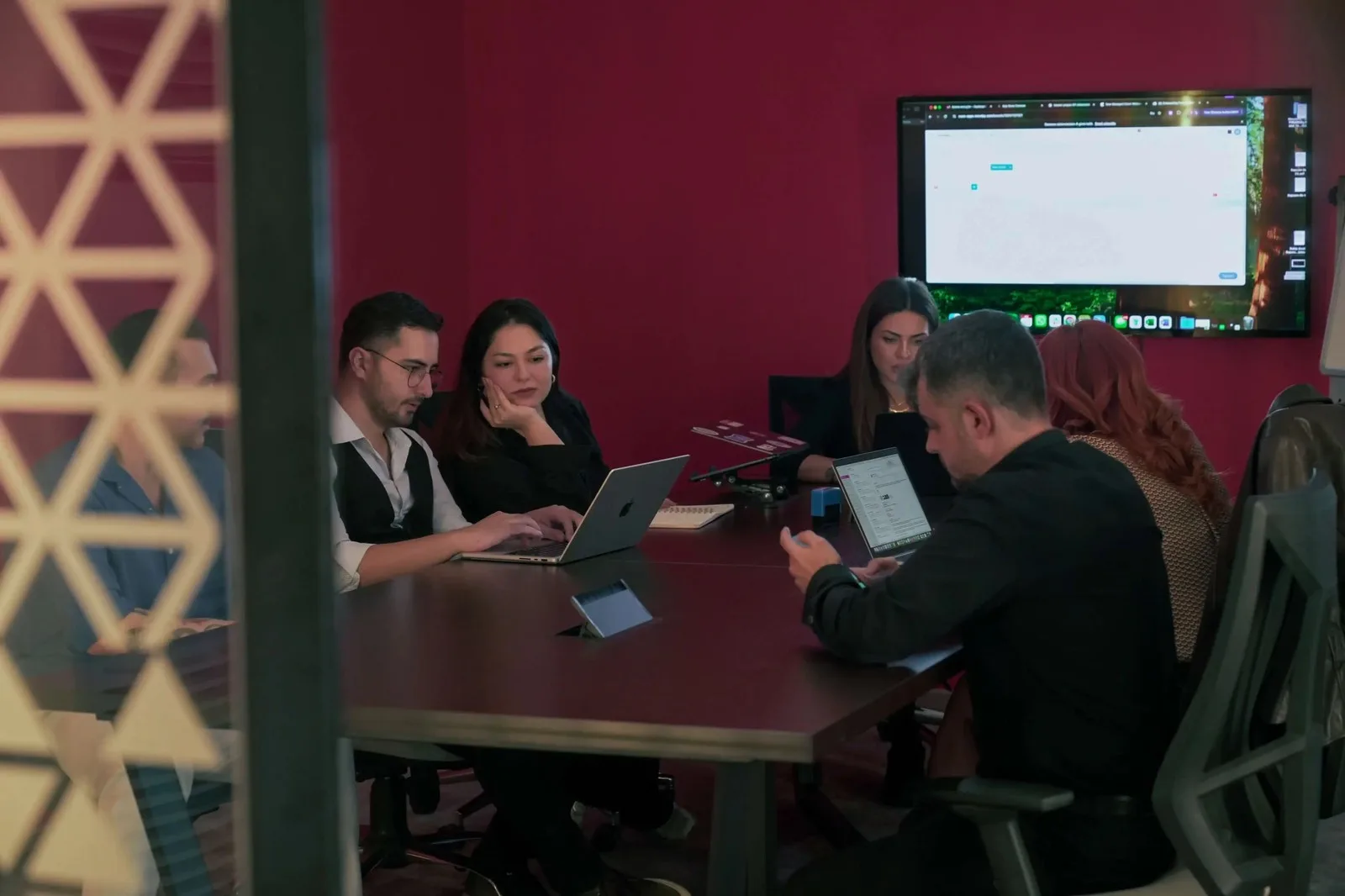Team meeting with laptops in a red walled meeting room