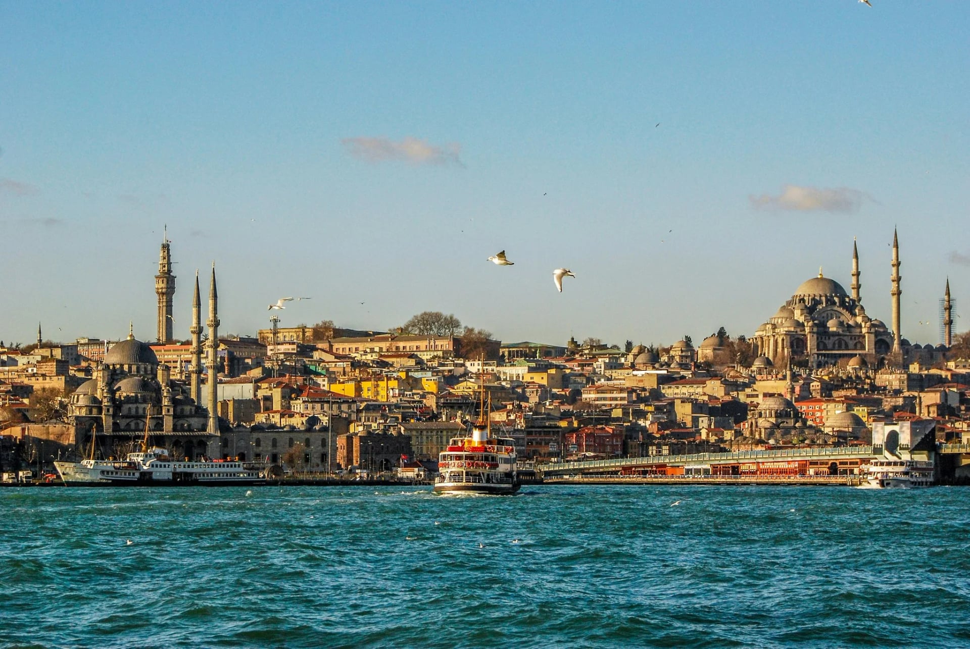Panoramic view of Istanbul skyline featuring the Bosphorus, historic mosques, ferry boats, and waterfront architecture on a clear day.