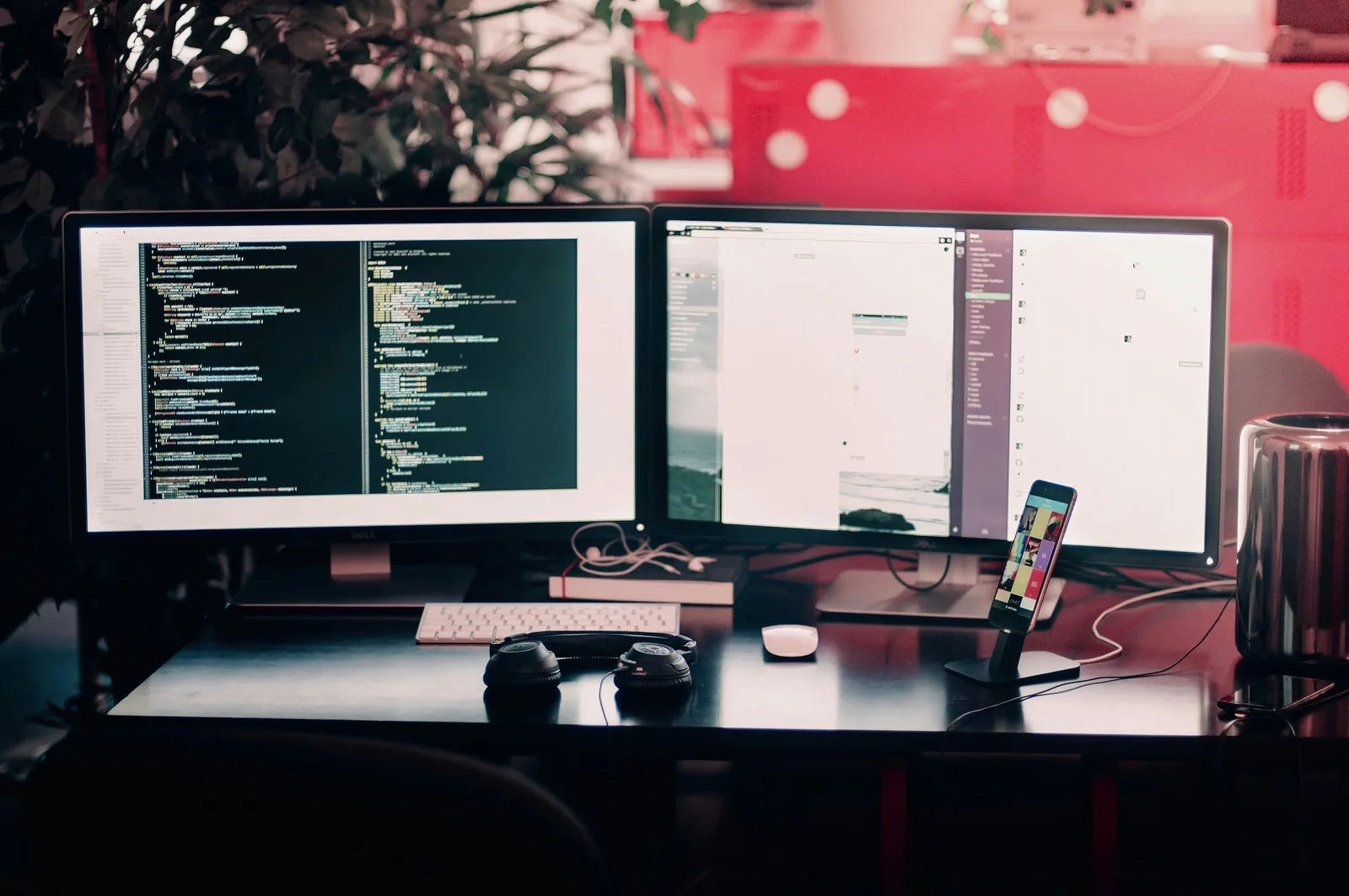 Developer desk with code on one monitor, headphones and a phone on a stand