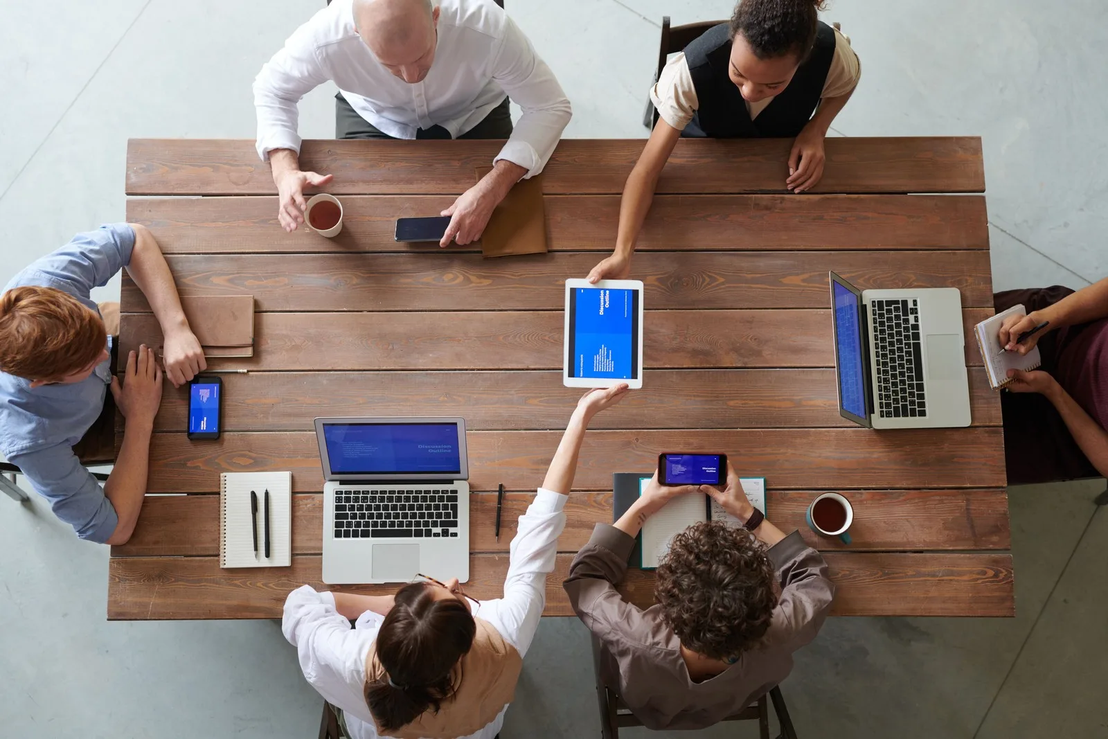 Business team collaborating with laptops, tablets, and smartphones during a digital strategy meeting in a modern workspace.