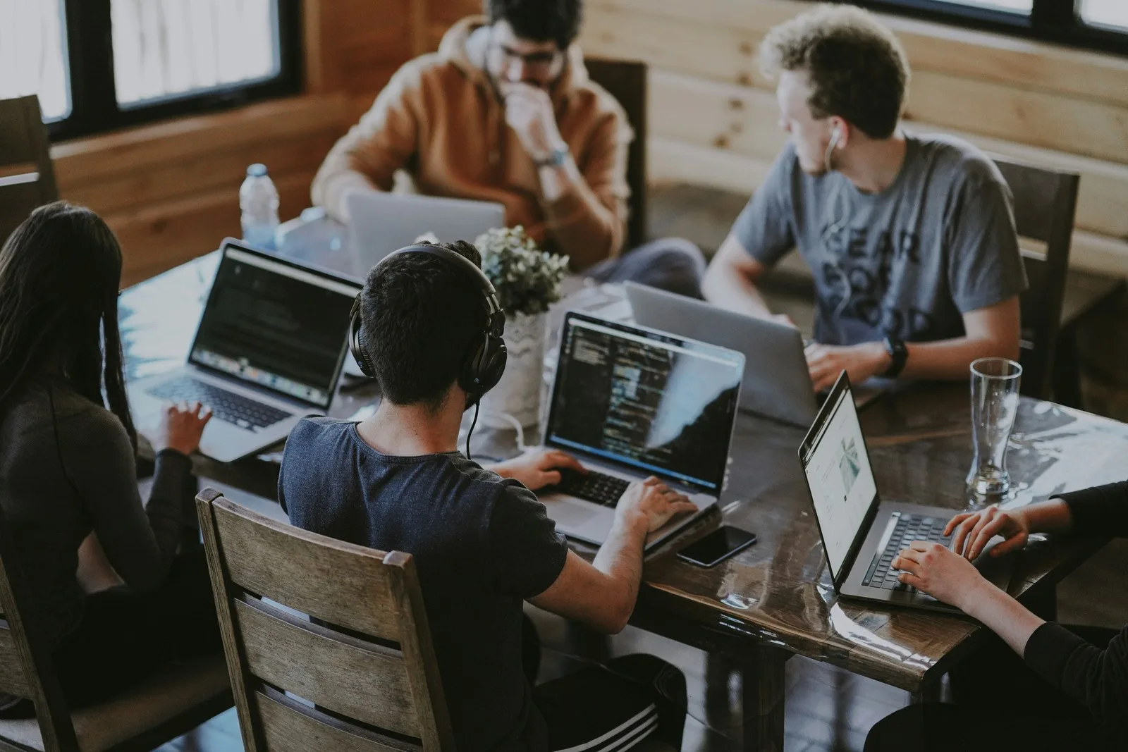 Software developers collaborating on coding projects using laptops in a modern workspace during a team meeting.