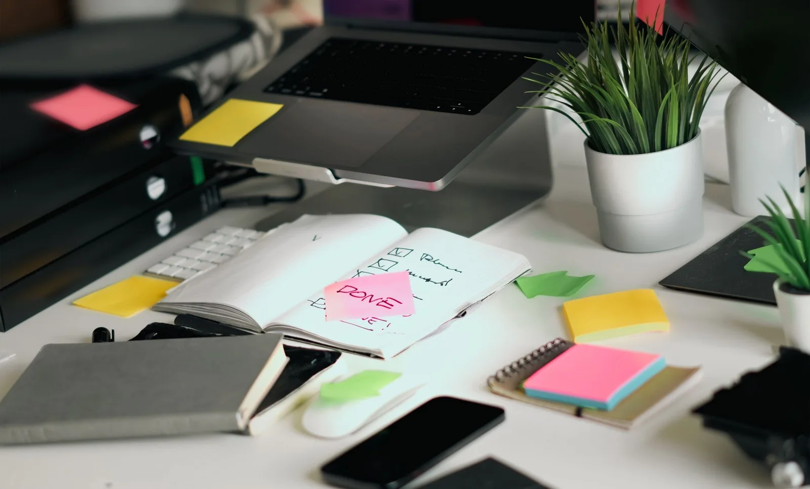 Modern workspace featuring a laptop, notebook, sticky notes, and project planning materials for agile workflow and task management.