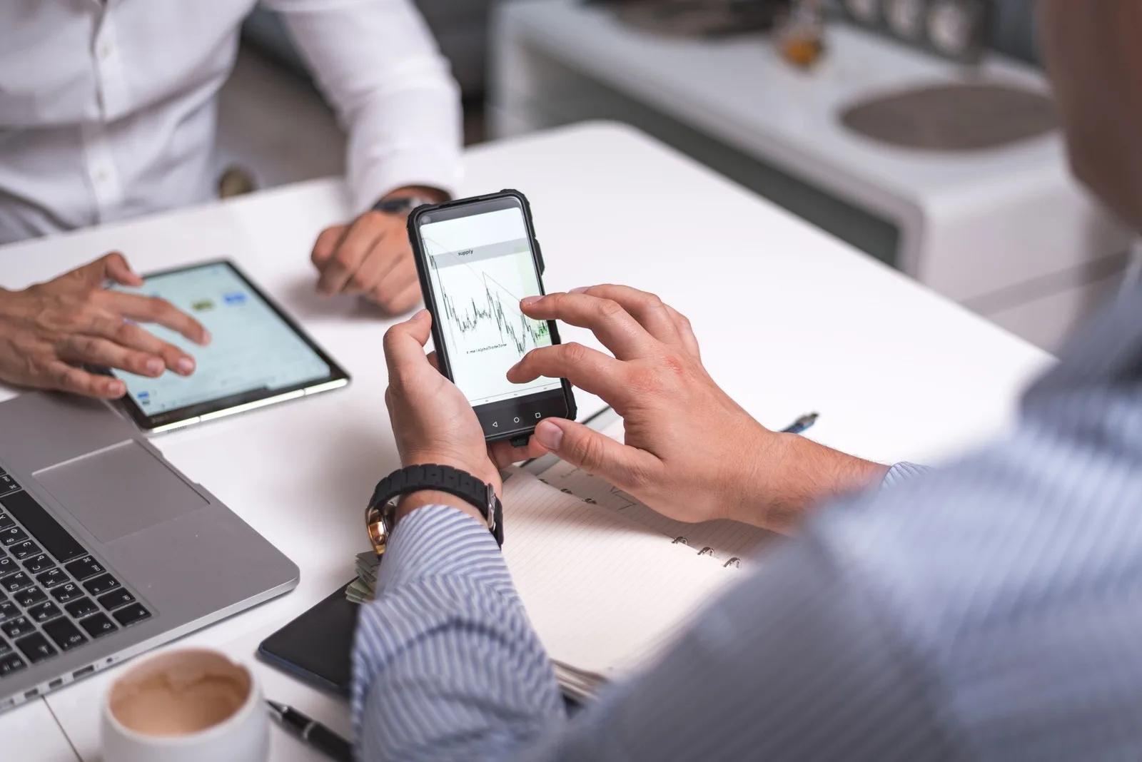 Business professionals reviewing mobile analytics and performance charts on a smartphone during a collaborative strategy meeting.