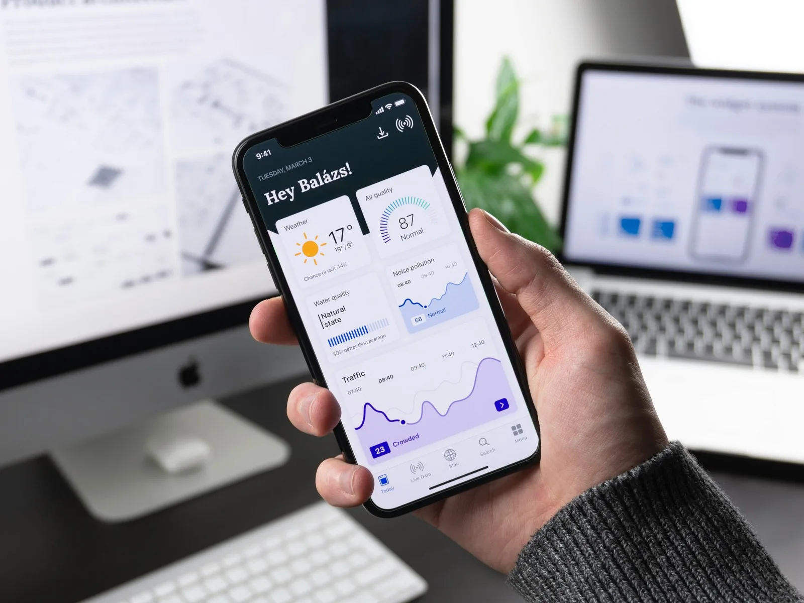 Phone showing a city data dashboard with weather, air quality and traffic at a desk